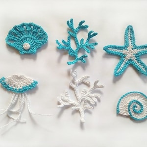 May include: A set of six crocheted sea-themed decorations in white and turquoise. The set includes a starfish, two types of coral, a seashell, a clam shell, and a jellyfish.