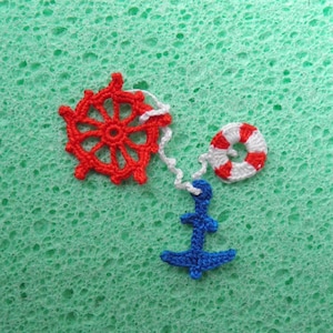 May include: A red and white crocheted nautical themed charm set with a wheel, life preserver, and anchor.