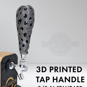May include: A 3D-printed tap handle with a unique, porous design in gray. The handle is mounted on a wooden block with a black base and a chrome tap. The text "3D PRINTED TAP HANDLE" is displayed.