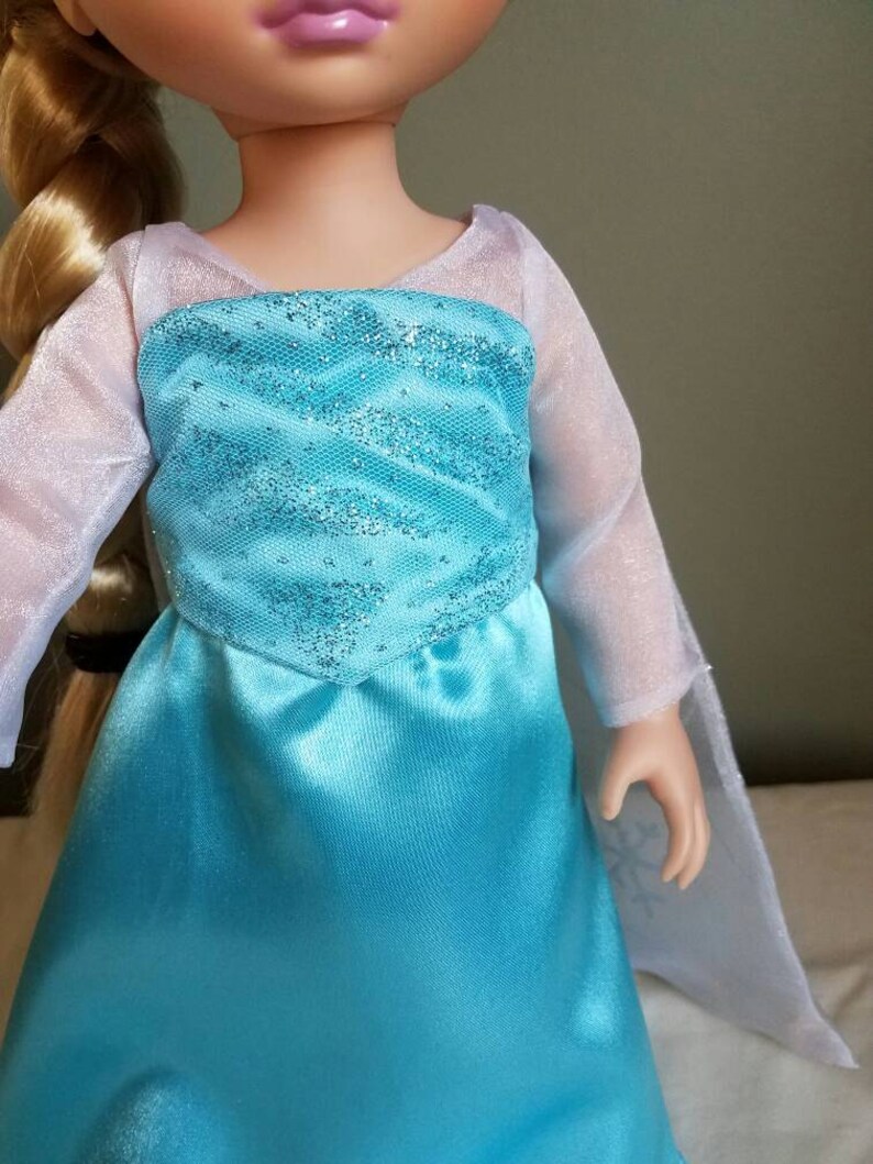 May include: A blue and white dress with a sparkly bodice and sheer sleeves. The dress is made of satin and has a princess-like silhouette.