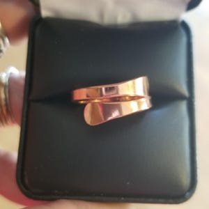 May include: A rose gold ring with a twisted design. The ring is in a black velvet box.