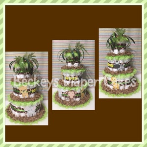 Op de afbeelding: Een drielaagse luiercake versierd met jungledieren thema's. De cake is ingepakt in bruin en wit gestreept stof en groen en wit gerimpeld stof. De bovenste laag heeft een groene plant, de middelste laag heeft het woord "Moss" in bruine letters, en de onderste laag heeft een bruine olifant, een bruine aap en een bruine leeuw.