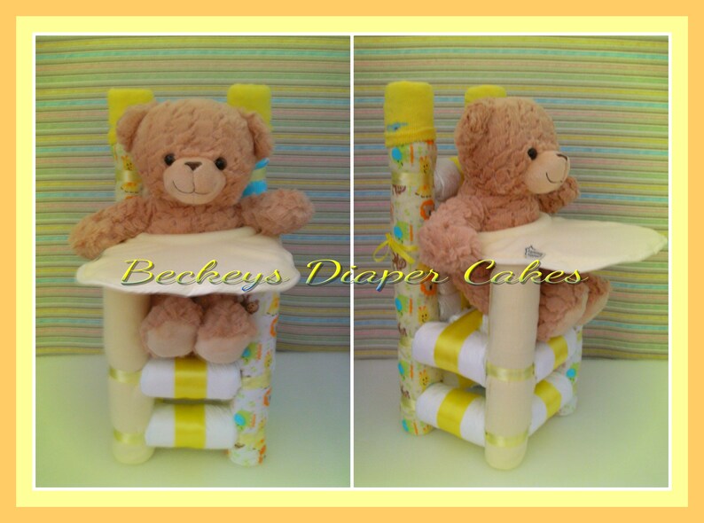 Op de afbeelding: Een gele en witte luiercake in de vorm van een hoge stoel met een bruine teddybeer die erin zit. De cake is versierd met geel en wit lint en een wit slabbetje. De cake is gemaakt van luiers, babydoekjes en andere babybenodigdheden.