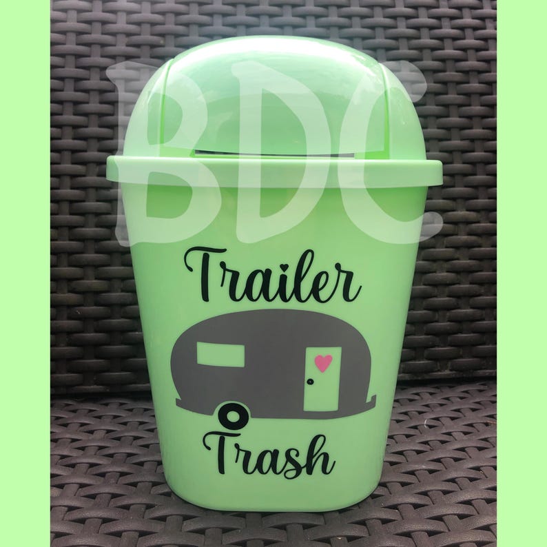 以下が含まれることがあります： トレーラーのシルエットと「Trailer Trash」というテキストが書かれた明るい緑色のゴミ箱です。