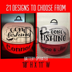 May include: Two battery-operated, round, fishing-themed decorations. Each has a white top with "Gone Fishing" text and a red base. One says "Connor" and the other says "Jayne & Jim". The decorations are 10 inches high and 11 inches wide.