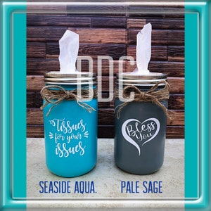 May include: Two mason jars painted in different colors, turquoise and gray, with tissue boxes inside. The turquoise jar has the text "Tissues for your issues" on it. The gray jar has the text "Bless You" with a heart shape around the word "Bless".