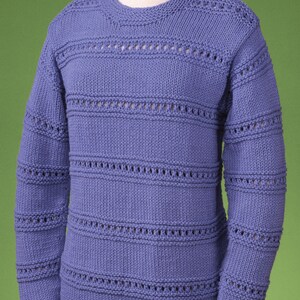 Puede incluir: Un suéter de punto azul claro con un delicado patrón de encaje. El suéter tiene cuello redondo y mangas largas.