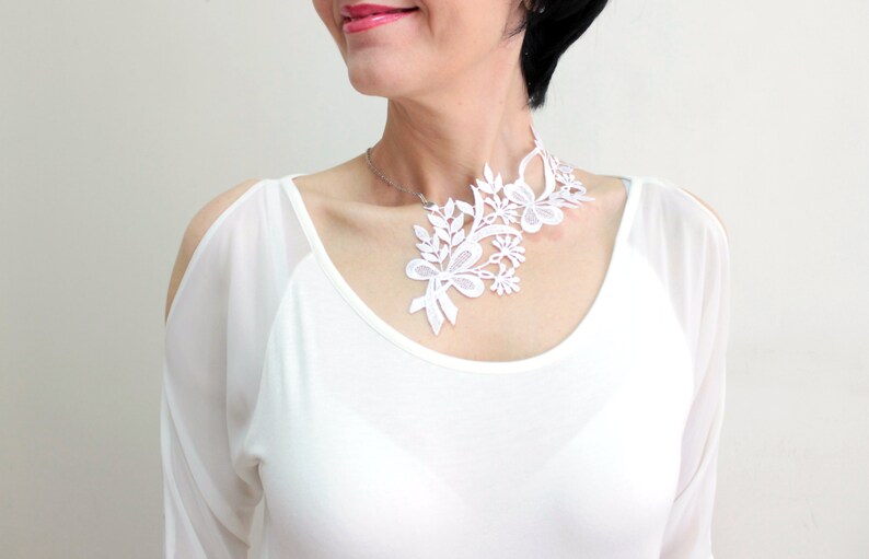 Puede incluir: Collar gargantilla de encaje blanco con dise&ntilde;o floral. El collar es delicado e intrincado, con un patr&oacute;n fluido de hojas y flores.