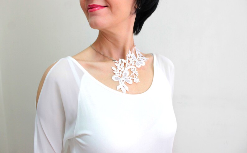 Puede incluir: Collar gargantilla de encaje blanco con dise&ntilde;o floral. El collar est&aacute; hecho de encaje blanco delicado y presenta una variedad de formas florales.
