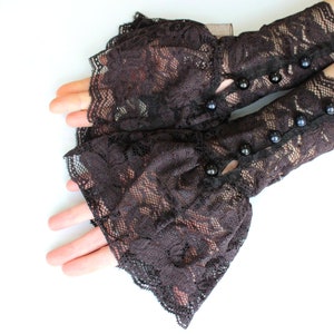 May include: A pair of black lace elbow length gloves with black button accents.