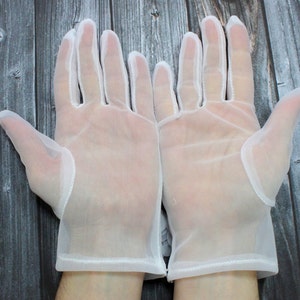 May include: A pair of white sheer gloves with a delicate lace trim. The gloves are made of a lightweight, breathable fabric and are perfect for special occasions.