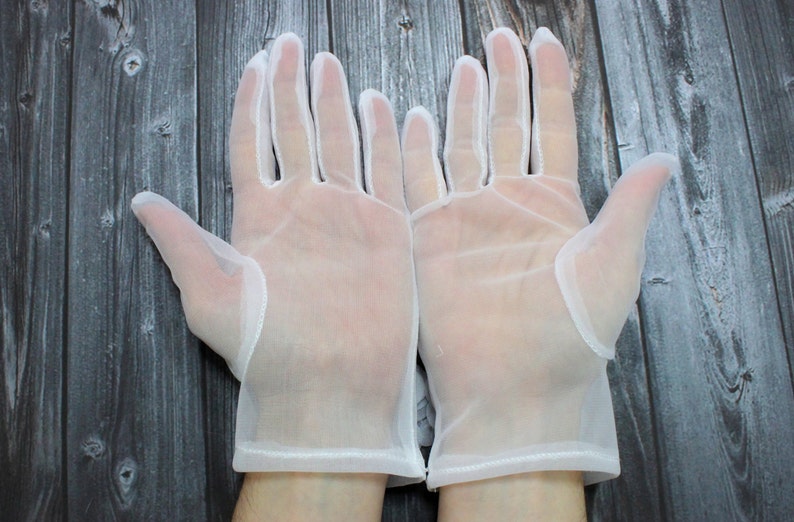 May include: A pair of white sheer gloves with a delicate lace trim. The gloves are made of a lightweight, breathable fabric and are perfect for special occasions.