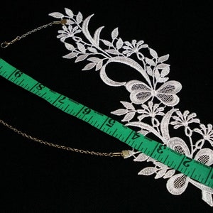 Puede incluir: Borde de encaje blanco con un dise&ntilde;o de mariposa y detalles florales. El borde mide aproximadamente 15 pulgadas de largo e incluye dos conectores de cadena de metal.