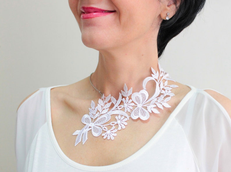 Puede incluir: Collar gargantilla de encaje blanco con un dise&ntilde;o floral. El collar es delicado e intrincado, con una variedad de flores y hojas.