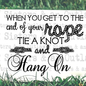 May include: White wooden sign with black text that reads "When you get to the end of your rope tie a knot and hang on". The text is surrounded by rope designs.