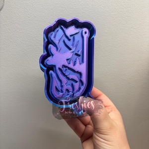 Puede incluir: Un cortador de galletas en forma de ciervo con cuernos, impreso en 3D en azul y morado. El cortador de galletas tiene un agujero en la parte superior para colgarlo.