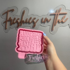 May include: Pink silicone mould with the text "Maybe she's born with it maybe it's ADHD" in a retro font.