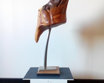 May include: A wooden sculpture of an animal's head, painted in shades of brown and gold, mounted on a silver stand. The sculpture is displayed on a white pedestal with the word "Animal" printed on it.