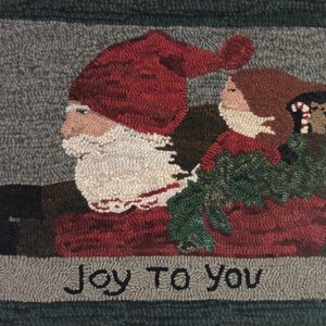 May include: A red and white hooked rug with a Santa Claus and a girl holding a green plant. The rug has the text "Joy To You" at the bottom.
