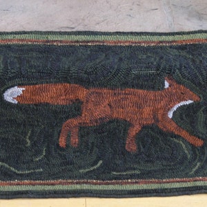 May include: A brown fox running through a green forest with two trees on either side. The trees have yellow leaves and are depicted in a stylized way. The rug is made of wool and has a dark green background.
