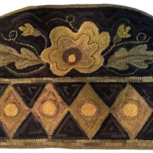 May include: Hand-hooked, semi-circular rug with a dark background. The rug features a large, central flower in shades of gold and brown, surrounded by green leaves. A border of diamond shapes in gold and brown adds a geometric element.