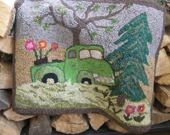 May include: A green truck with a bed full of flowers drives past a green pine tree. The truck is on a brown and green rug with a brown border.