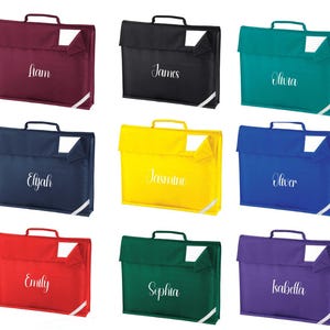 May include: A collection of nine school satchels in a range of colours: burgundy, black, teal, navy, yellow, red, green, and purple. Each satchel features a handle, a flap, and a white name tag. Names such as Liam, James, Olivia, Elijah, Jasmine, Oliver, Emily, Sophia, and Isabella are printed on each.