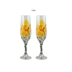 Può includere: Set di due flute da champagne con steli e basi argentate. Gli steli sono intrecciati e hanno un design a vite. Le flute sono riempite con carta velina gialla stropicciata.