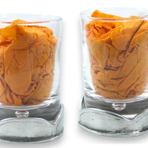 Könnte beinhalten: Zwei klare Schnapsgläser mit silbernen Sockeln, jedes mit einem zerknitterten orangefarbenen Taschentuch.