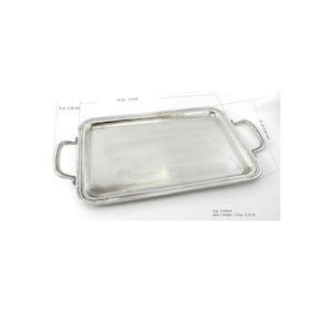Op de afbeelding: Een rechthoekige zilveren serveerschaal met twee handgrepen. De schaal is 33 cm lang en 23 cm breed. De schaal heeft een opstaande rand en is gemaakt van glanzend metaal. De schaal weegt 1,9 kg.
