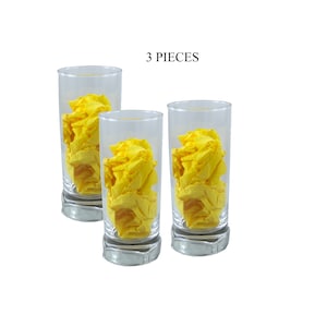 Puede incluir: Tres vasos de vidrio transparente con un pañuelo de papel amarillo arrugado dentro de cada uno. El texto "3 PIECES" está impreso encima de los vasos.
