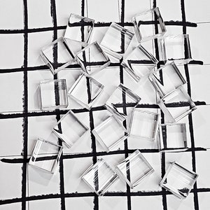 May include: A collection of clear glass square blocks arranged on a white and black grid background.