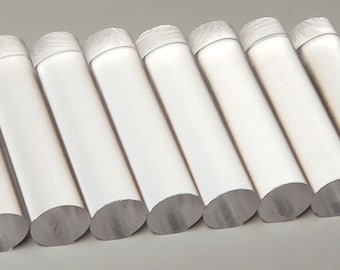 May include: Seven clear acrylic rods, each with a rounded end, are arranged in a row on a gray surface.