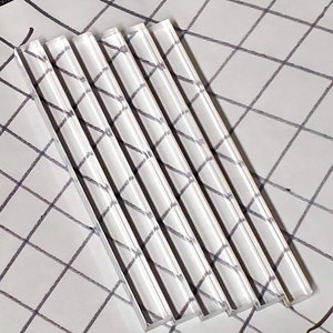 May include: Five clear acrylic rods, stacked on top of each other, with a smooth, polished finish.