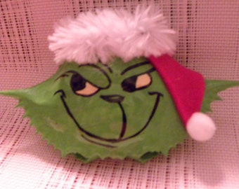 Grinch fur and felt trim painted on a crab shell ornament. Packaged in a plastic container with coordinated shred