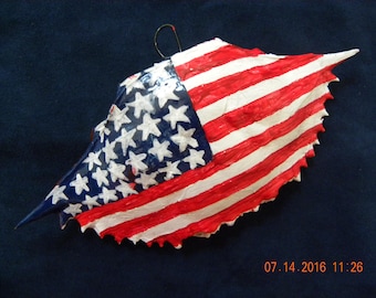 The American flag is handpainted on a crab shell Christmas ornament.  It comes packaged in a plastic container with a coordinated shred