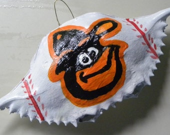 Baltimore Oriole head on baseball Painted Crab Shell. Packaged in a plastic container with coordinated shred