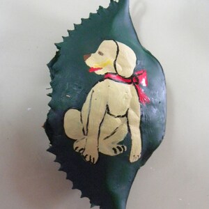 Yellow Lab with big red bow green background painted on crab shell ornament. Comes in plastic container ready to wrap