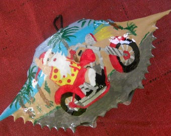 Santa motorcycle in Hawiian shirt painted crab shell ornament. Packaged in a plastic container with coordinated shred