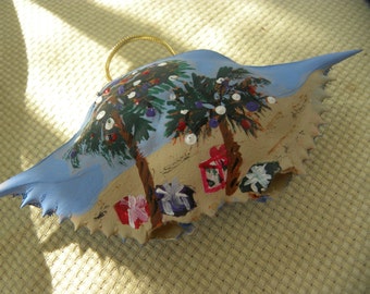 Christmas Palm Trees with presents  painted on a crab shell ornament. Packaged in a plastic container with coordinated shred