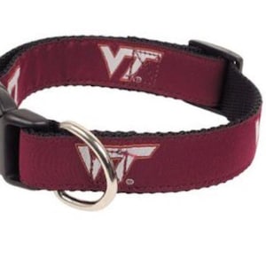 May include: Burgundy dog collar with a white VT logo. The collar has a black buckle and a silver D-ring.