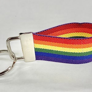 May include: A rainbow-colored key chain with a silver key ring and a silver clasp. The rainbow colors are red, orange, yellow, green, blue, and purple.
