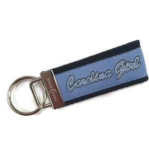 May include: A blue and black key chain with the text "Carolina Girl" embroidered on it.