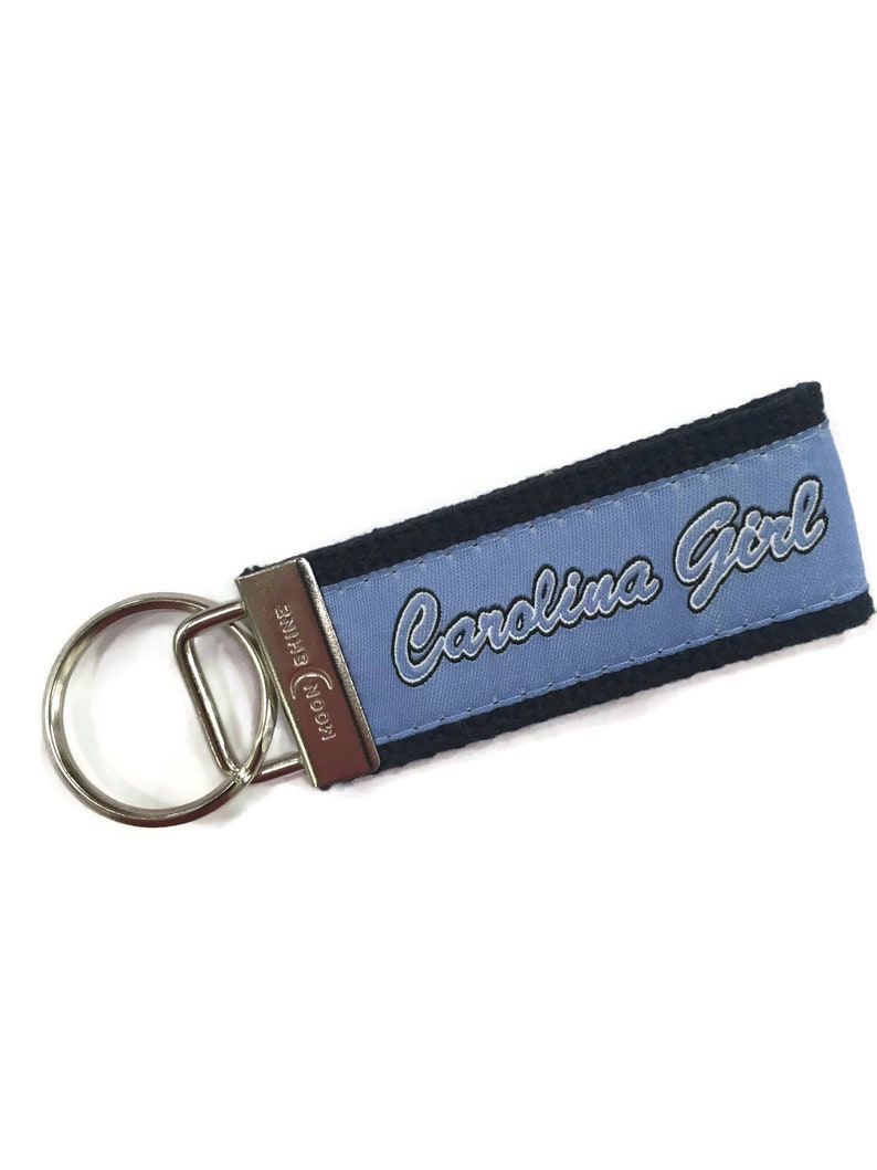 May include: A blue and black key chain with the text "Carolina Girl" embroidered on it.