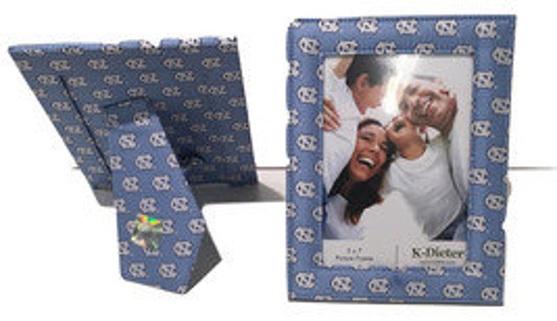 May include: A blue picture frame with a white and blue pattern. The frame is 4x6 inches and has a stand on the back. The frame is made by K. Carter.
