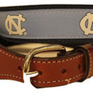May include: A blue and white woven belt with a brown leather buckle. The belt features the letters "NC" repeated on the woven fabric.