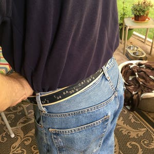May include: A blue jean belt with black text that reads "37 1/2 34 BA 55 1 CAT 84 8 7 69".