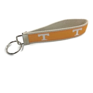 May include: A white and orange key chain with a white "T" on the orange stripe.
