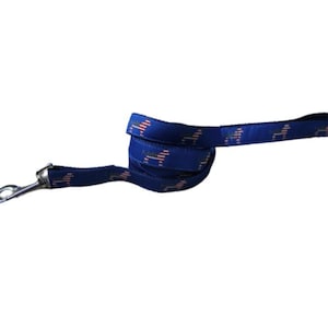 May include: A blue dog leash with a repeating pattern of American flags. The leash has a silver clip.