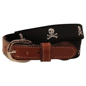 May include: A black woven belt with a brown leather buckle and white embroidered skull and crossbones designs.
